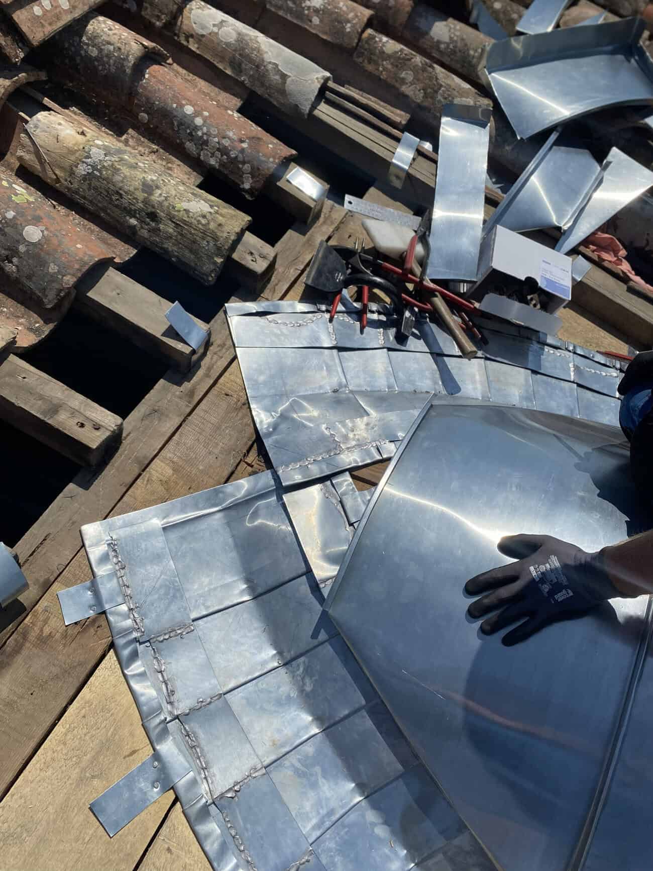 Metal roofing components being installed on a wooden roof structure.