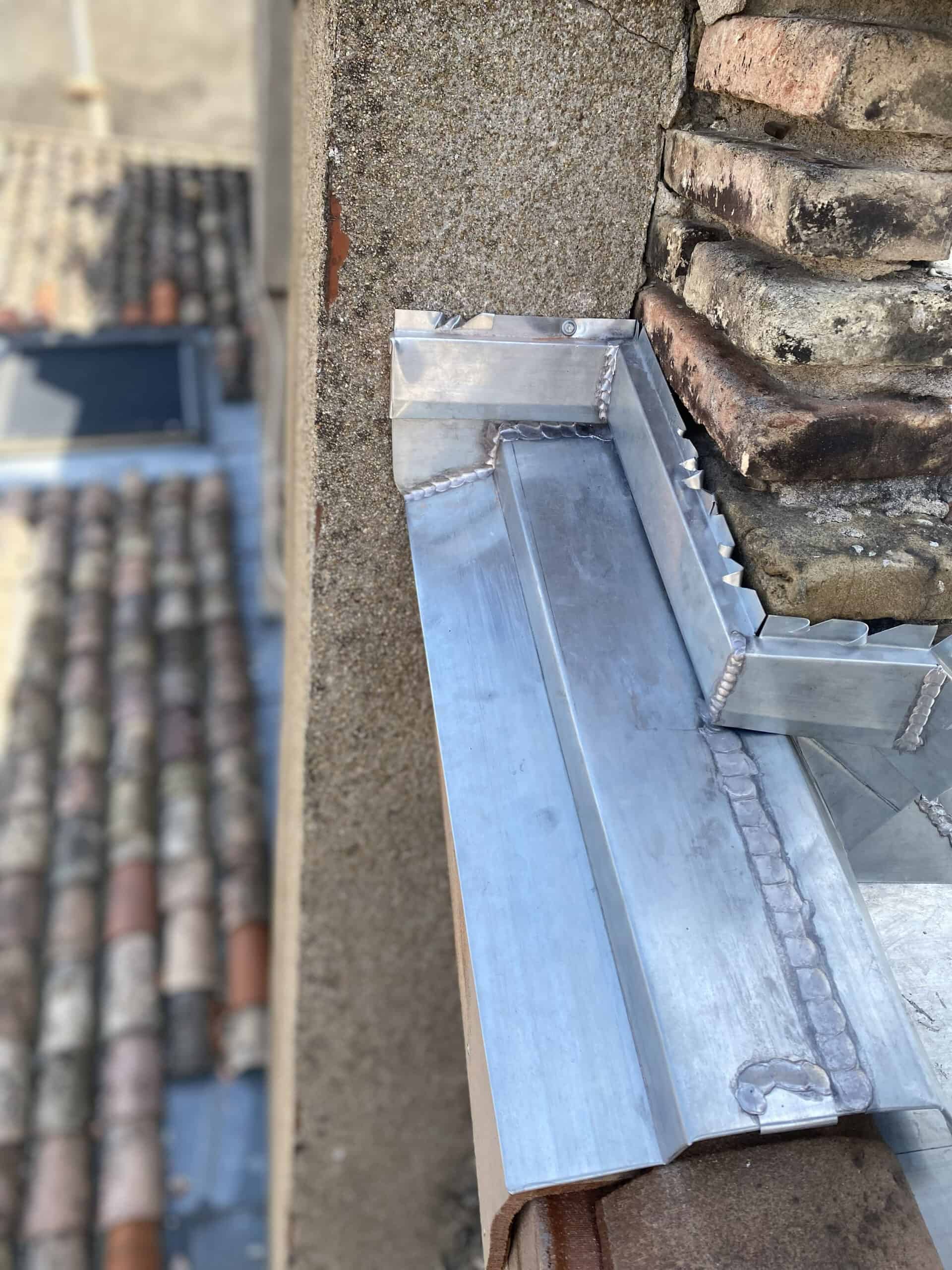 Metal roof flashing around chimney for waterproofing and protection.
