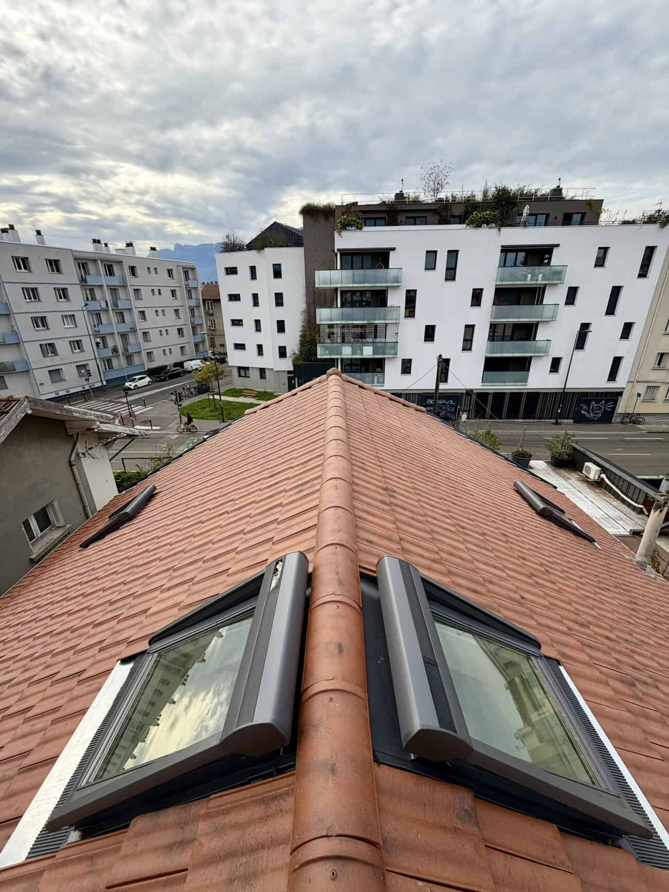 Roof with skylights and red tiles in an urban residential setting.